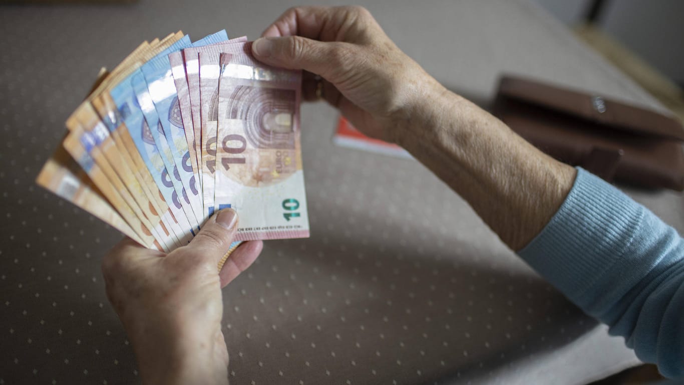 Ältere Person mit Bargeld (Symbolbild): In Karlsruhe sollen Betrüger über Hunderttausend Euro erschwindelt haben.