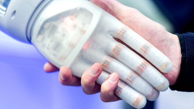 Ein Mann hält am Stand des Unternehmens Festo auf der Hannover Messe die Hand eines bionischen Roboters. Ein Mann hält am Stand des Unternehmens Festo auf der Hannover Messe die Hand eines bionischen Roboters.