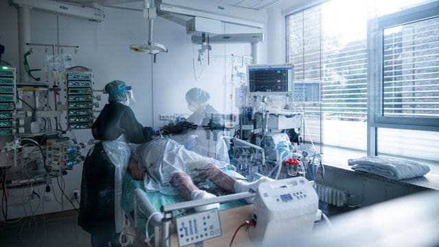 Mitarbeiterinnen der Pflege in Schutzausrüstung betreuen einen Corona-Patienten. Mitarbeiterinnen der Pflege in Schutzausrüstung betreuen einen Corona-Patienten.
