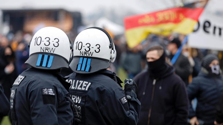 Polizisten beobachten Hooligans auf einer Querdenken-Demo in Düsseldorf: Der NRW-Verfassungsschutz sieht eine Radikalisierung der Gruppierung.