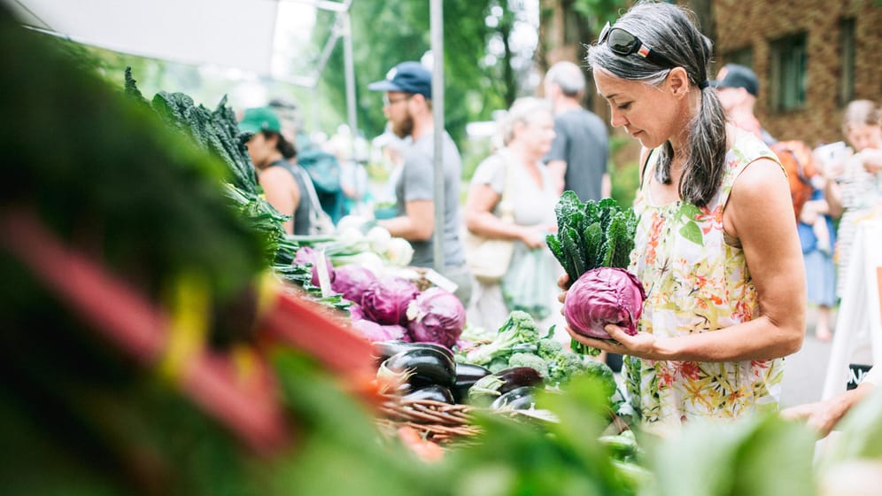Eine Frau auf dem Wochenmarkt: Obst, Gemüse, Kräuter und Salat sind reich an wertvollen Vitaminen und helfen dem Körper, gesund zu bleiben.