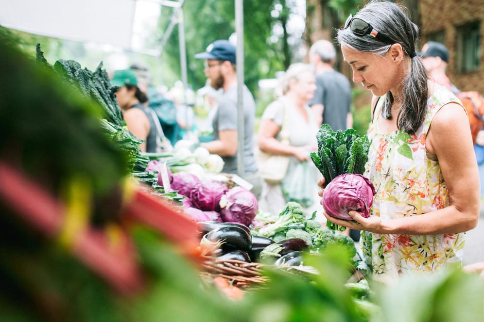 Eine Frau auf dem Wochenmarkt: Obst, Gemüse, Kräuter und Salat sind reich an wertvollen Vitaminen und helfen dem Körper, gesund zu bleiben.
