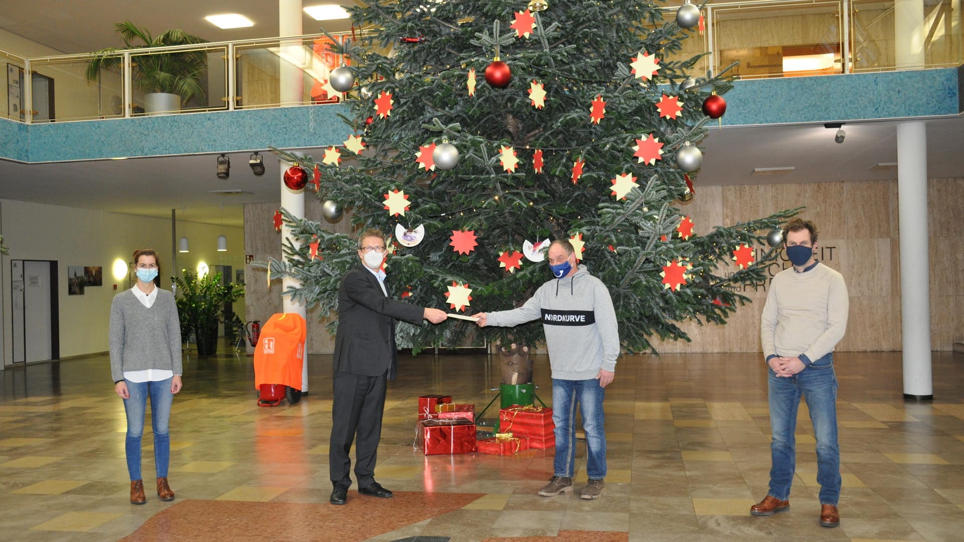 Jasmin Hinze, Klaus Mohrs, Thomas Krücker und Michael Bahn (von links) vor dem Weihnachtsbaum in der Bürgerhalle: OB Mohrs überreichte dem Tagestreff "Carpe Diem" eine Spende.