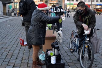 Eine Frau schenkt einem Obdachlosen ein heißes Getränk ein. In der Weihnachtszeit verteilt Linda Rennings auch Geschenke an die Obdachlosen.