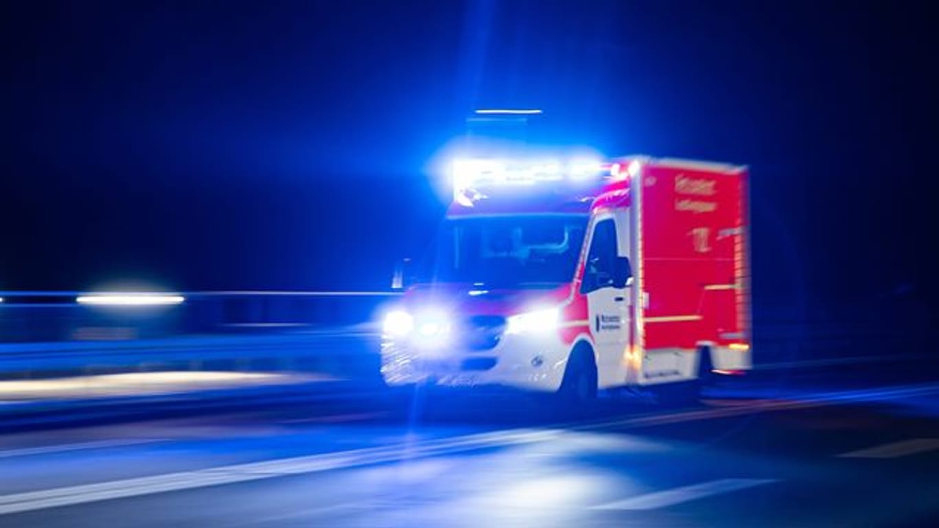 Ein Rettungswagen der Feuerwehr fährt mit Blaulicht durch eine Straße (Symbolbild). Ein junger Mann wurde in Düsseldorf mit einem Messer schwer verletzt.