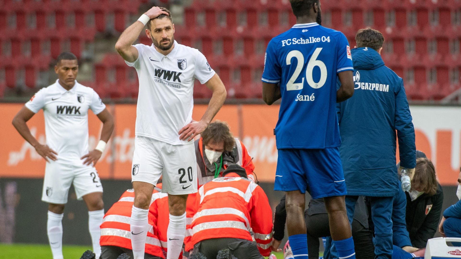 Bundesliga: Augsburgs Daniel Caligiuri (l) fast sich an den Kopf, während Schalkes Mark Uth behandelt wird.