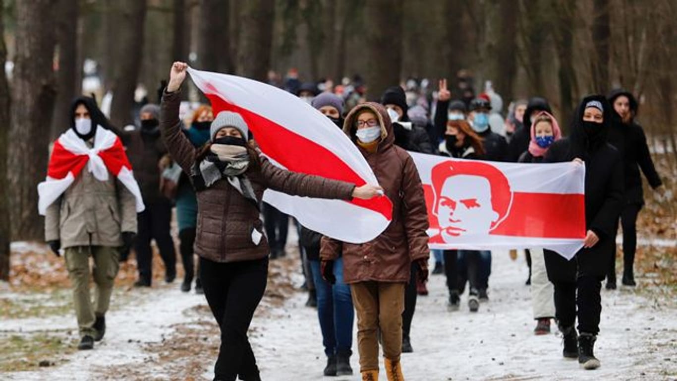 Demonstranten mit Mund-Nasen-Schutz tragen bei einer Kundgebung in Minsk, auf der sie den Rücktritt von Machthaber Lukaschenko fordern, Fahnen in den Farben der früheren belarussischen Nationalflagge.