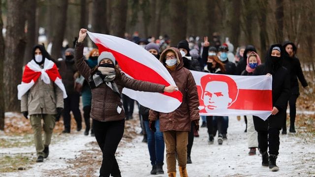 Demonstranten mit Mund-Nasen-Schutz tragen bei einer Kundgebung in Minsk, auf der sie den Rücktritt von Machthaber Lukaschenko fordern, Fahnen in den Farben der früheren belarussischen Nationalflagge.