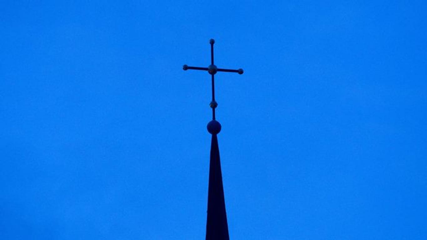 Das Kreuz einer evangelisch-lutherischen Kirche ist in der Abenddämmerung zu sehen.