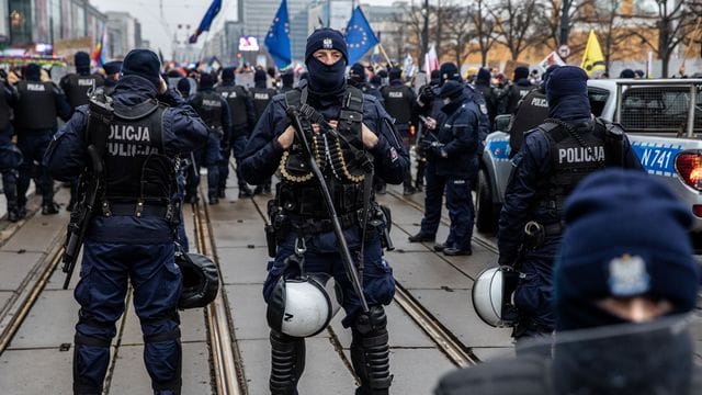 Polizisten in Schutzuniform stehen während einer Demonstration in der Hauptstadt Warschau Wache. Polizisten in Schutzuniform stehen während einer Demonstration in der Hauptstadt Warschau Wache.