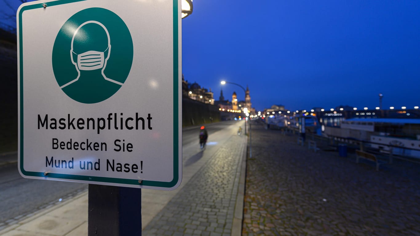 Ein Hinweisschild auf die Maskenpflicht hängt in Dresden: Die täglichen Zahlen des RKI bleiben weiter auf hohem Niveau