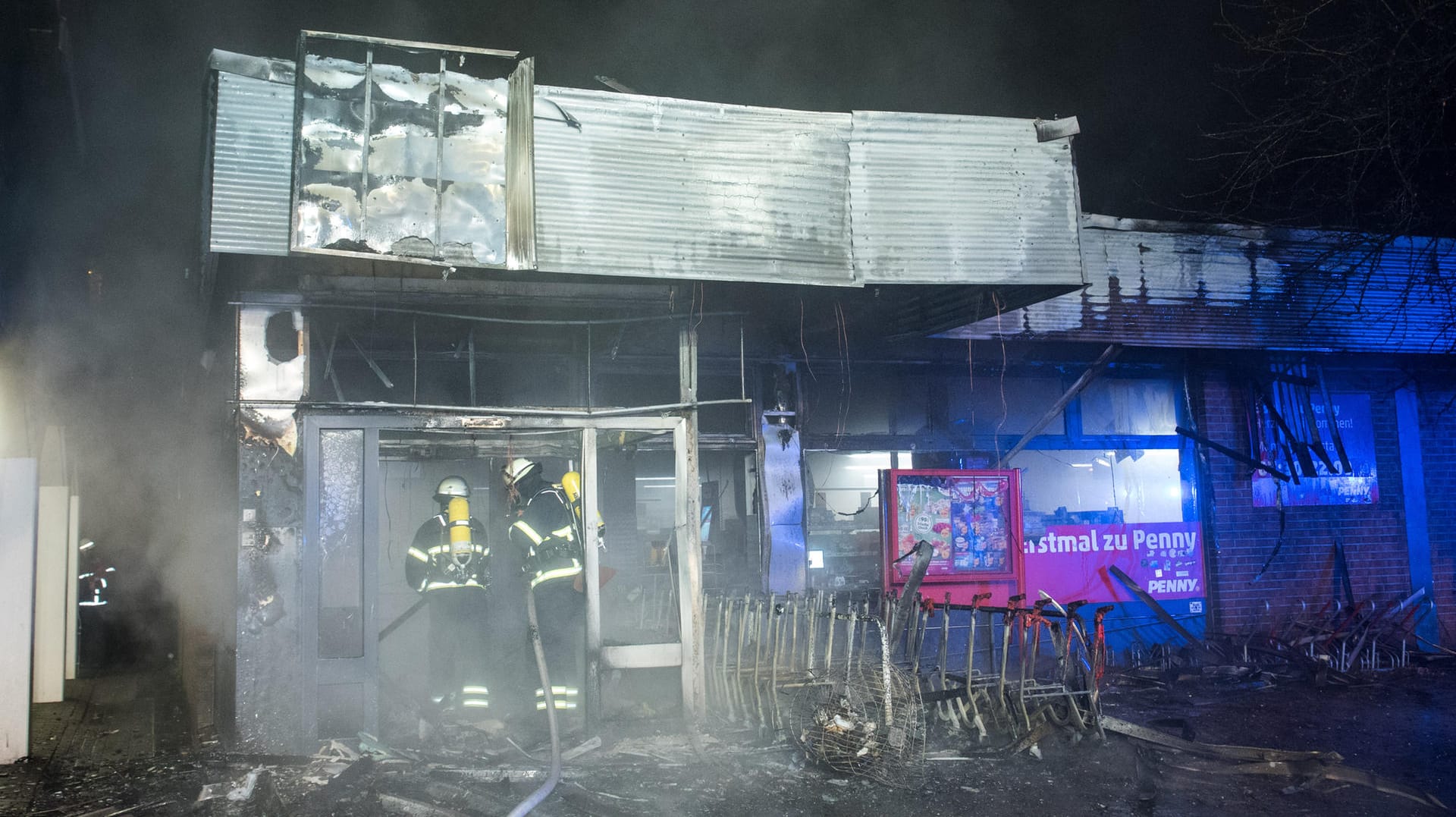 Feuerwehrleute sind im Hamburger Stadtteil Veddel während eines Brandes in einem Supermarkt mit Löscharbeiten beschäftigt: Dort hatte wohl der Überstand für die Einkaufswagen gebrannt und das Feuer ausgelöst. Feuerwehrleute sind im Hamburger Stadtteil Veddel während eines Brandes in einem Supermarkt mit Löscharbeiten beschäftigt: Dort hatte wohl der Überstand für die Einkaufswagen gebrannt und das Feuer ausgelöst.