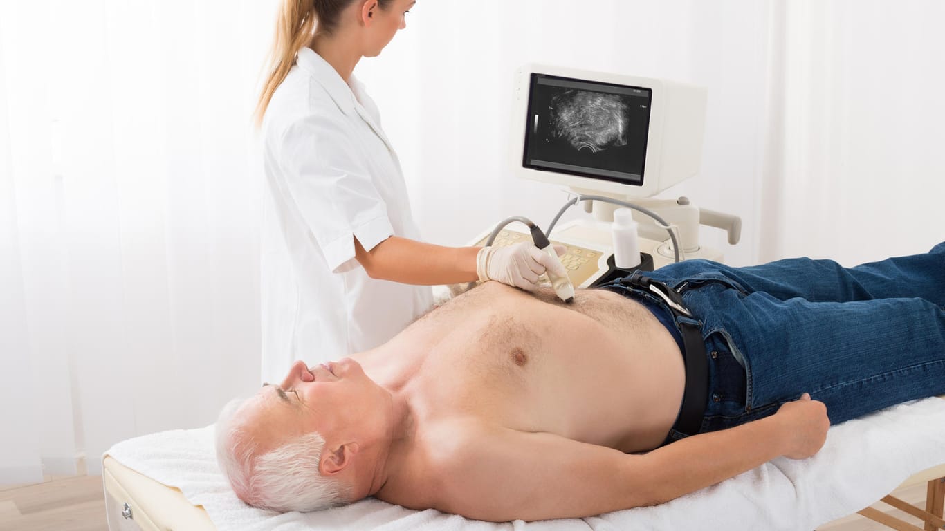 Ärztin untersucht den Bauchraum eines männlichen Patienten auf ein Bauchaortenaneurysma.
