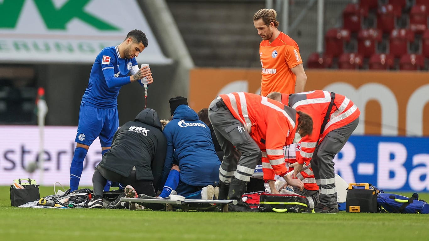 Mark Uth wird auf dem Spielfeld in Augsburg medizinisch behandelt: Der Schalker hatte das Bewusstsein verloren.