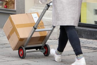 Eine Frau schiebt ein Paket (Symbolbild): In Bayern plant das Kabinett eine Zustellung am vierten Adventssonntag.