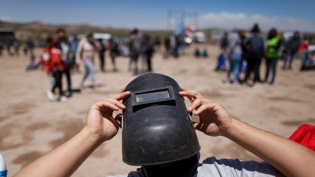 Mit einer Schweißermaske als Schutz wartet ein Mann im argentinischen Piedra Del Aguila auf eine totale Sonnenfinsternis. Mit einer Schweißermaske als Schutz wartet ein Mann im argentinischen Piedra Del Aguila auf eine totale Sonnenfinsternis.