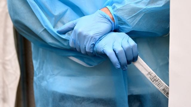 Medizinisches Fachpersonal wartet in Berlin darauf, einen Abstrich für einen Antigen-Schnelltest zu entnehmen.