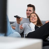 Ein Mann und eine Frau beim Fernsehen: Beim TV-Kauf sollten Nutzer einiges beachten.