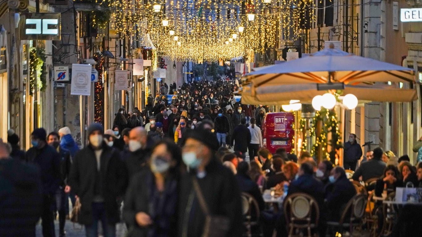Rom: Zahlreiche Menschen mit Mund-Nasen-Schutz gehen eine weihnachtlich geschmückte Einkaufsstraße in der Innenstadt entlang.