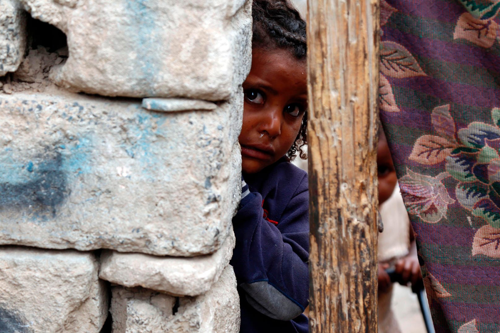 Ein kleines Mädchen blickt hinter einer Mauer in einem Slum eines Kriegsgebiets von Sanaa im Jemen hervor: Jemen das Land mit dem höchsten Risiko einer humanitären Notlage im Jahr 2021.