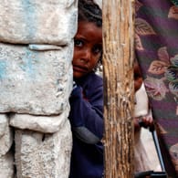 Ein kleines Mädchen blickt hinter einer Mauer in einem Slum eines Kriegsgebiets von Sanaa im Jemen hervor: Jemen das Land mit dem höchsten Risiko einer humanitären Notlage im Jahr 2021.