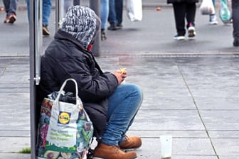 Eine obdachlose Person bittet in einer Einkaufsstraße um Geld (Symbolbild): Die kalte, teils lebensgefährliche Jahreszeit macht Wärme zwingend erforderlich. Deswegen startet in Wuppertal nun wieder die Kälte-Hotline.