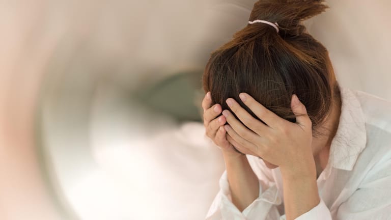 Eine Frau stützt ihren Kopf mit ihren Händen: Schwindelgefühl kann viele Ursachen haben. Auch ernste Krankheiten können dahinterstecken.