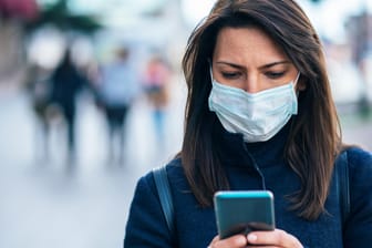 Eine Frau mit Smartphone: Apps können während der Corona-Pandemie helfen.