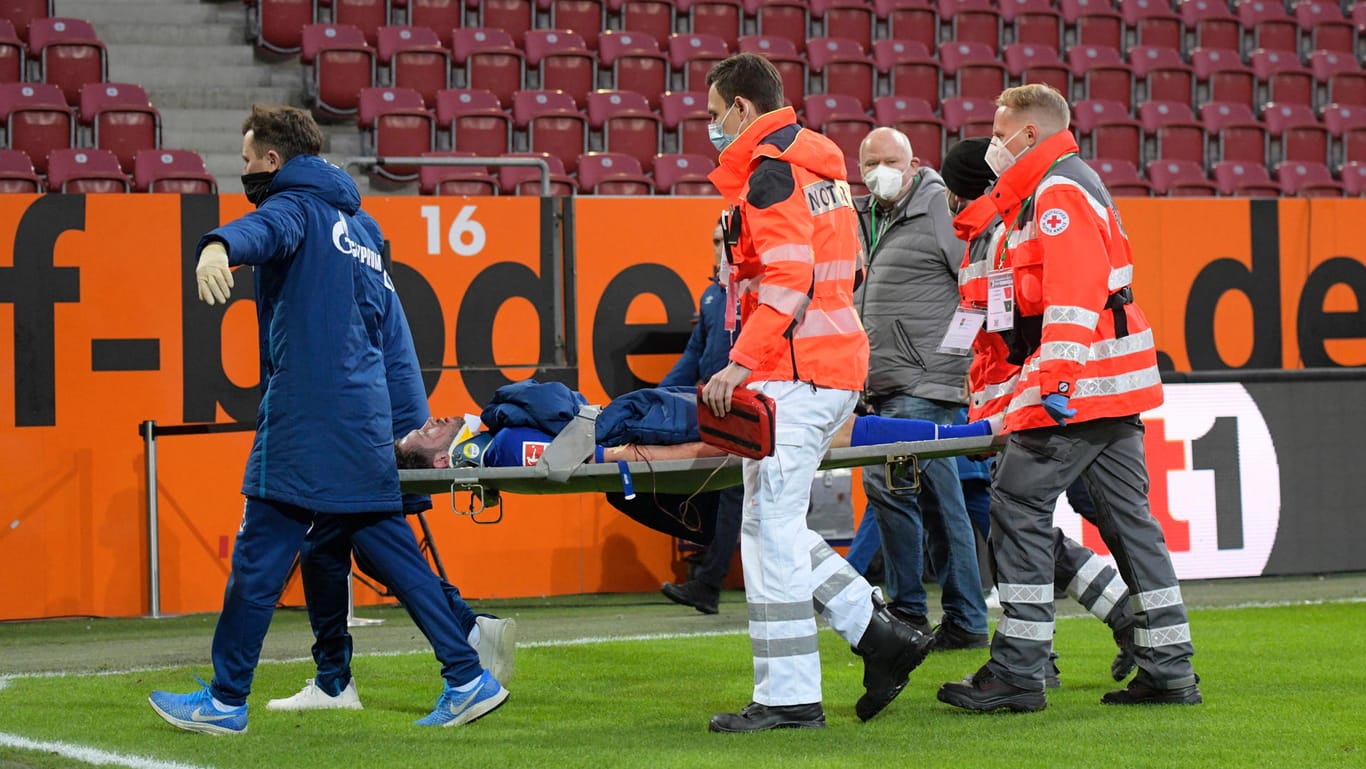 Mark Uth: Der Schalker wird nach einer Kopfverletzung im Spiel in Augsburg von Betreuern und Ärzten auf einer Trage aus dem Stadion gebracht.