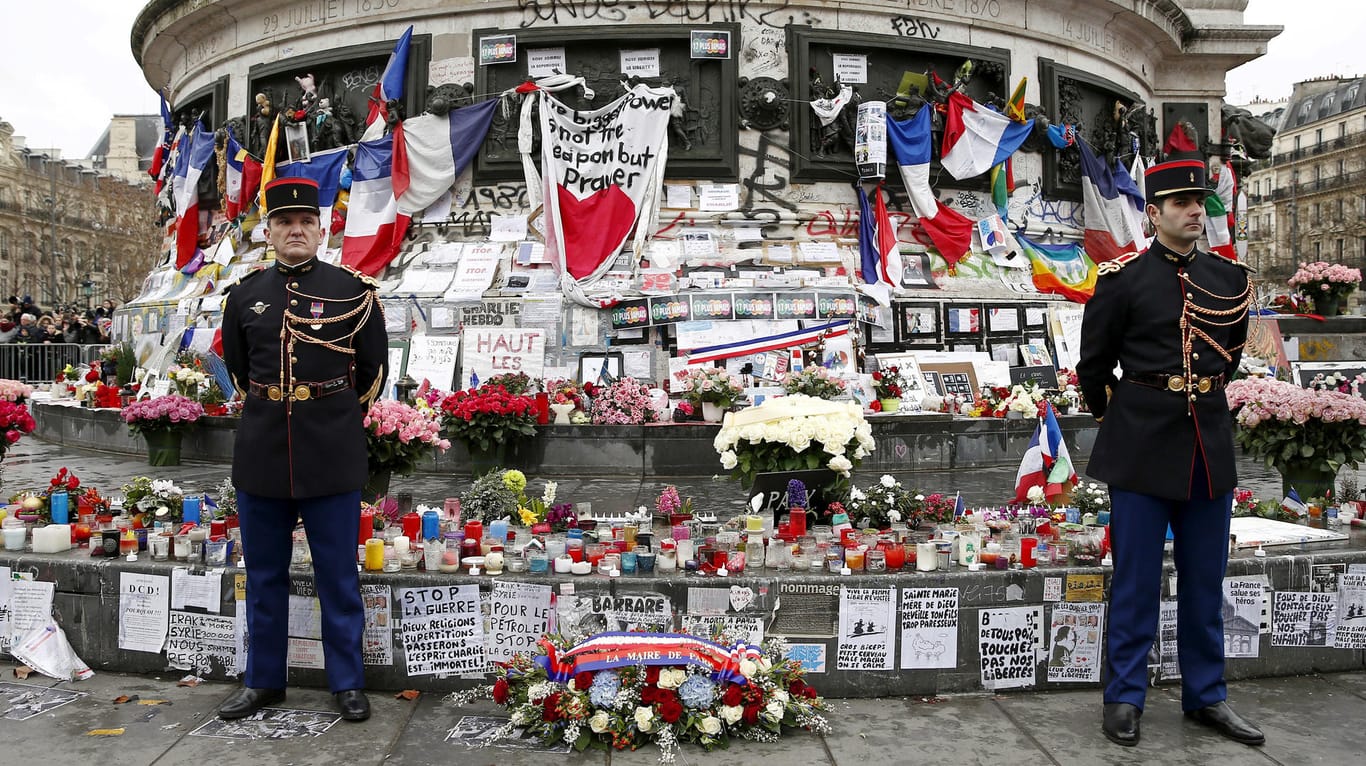 Gedenken an die Anschlagsopfer: Polizisten stehen am 10. Januar 2016 auf dem Place de la Republique vor Blumen, Kerzen und Botschaften, die Trauernde hinterlassen haben.