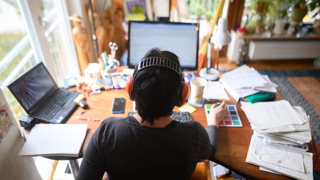 Eine Frau arbeitet mit Hörschutz im Homeoffice.