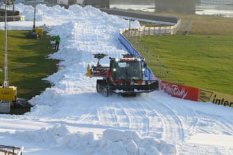 Ein Pistenbully präpariert am Elbufer eine künftige Wettkampfstrecke mit Kunstschnee: Trotz des Lockdowns wird der Skilanglauf-Weltcup in Dresden durchgeführt.
