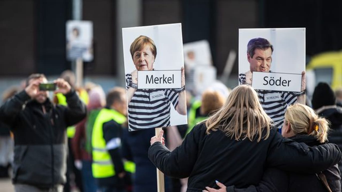 Bundeskanzlerin Merkel (CDU) und Bayerns Ministerpräsident Söder (CSU) in "Sträflingskleidung": Die Fotomontage trägt eine Frau auf einer Demonstration.