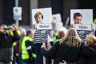 Bundeskanzlerin Merkel (CDU) und Bayerns Ministerpräsident Söder (CSU) in "Sträflingskleidung": Die Fotomontage trägt eine Frau auf einer Demonstration.