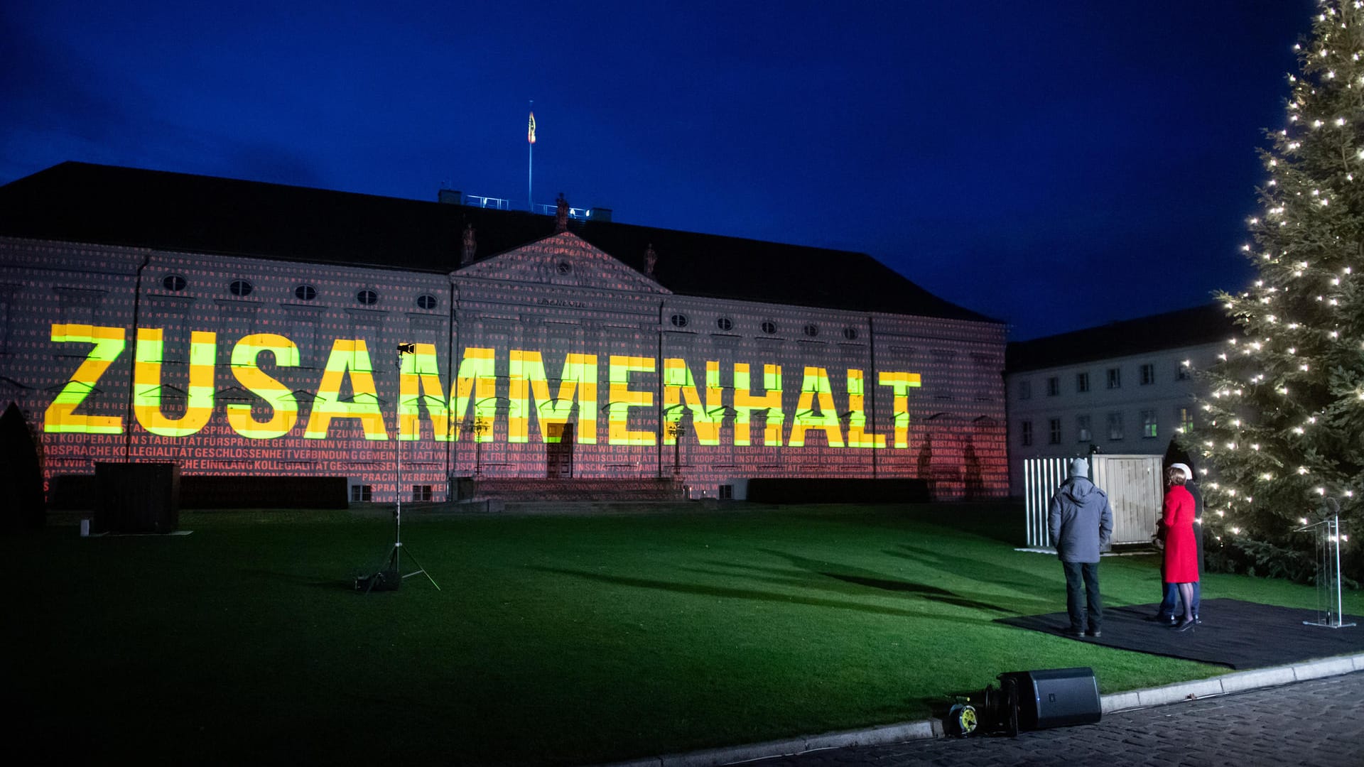 Bundespräsident Frank-Walter Steinmeier und seine Frau Elke Büdenbender vor dem illuminierten Schloss Bellevue.