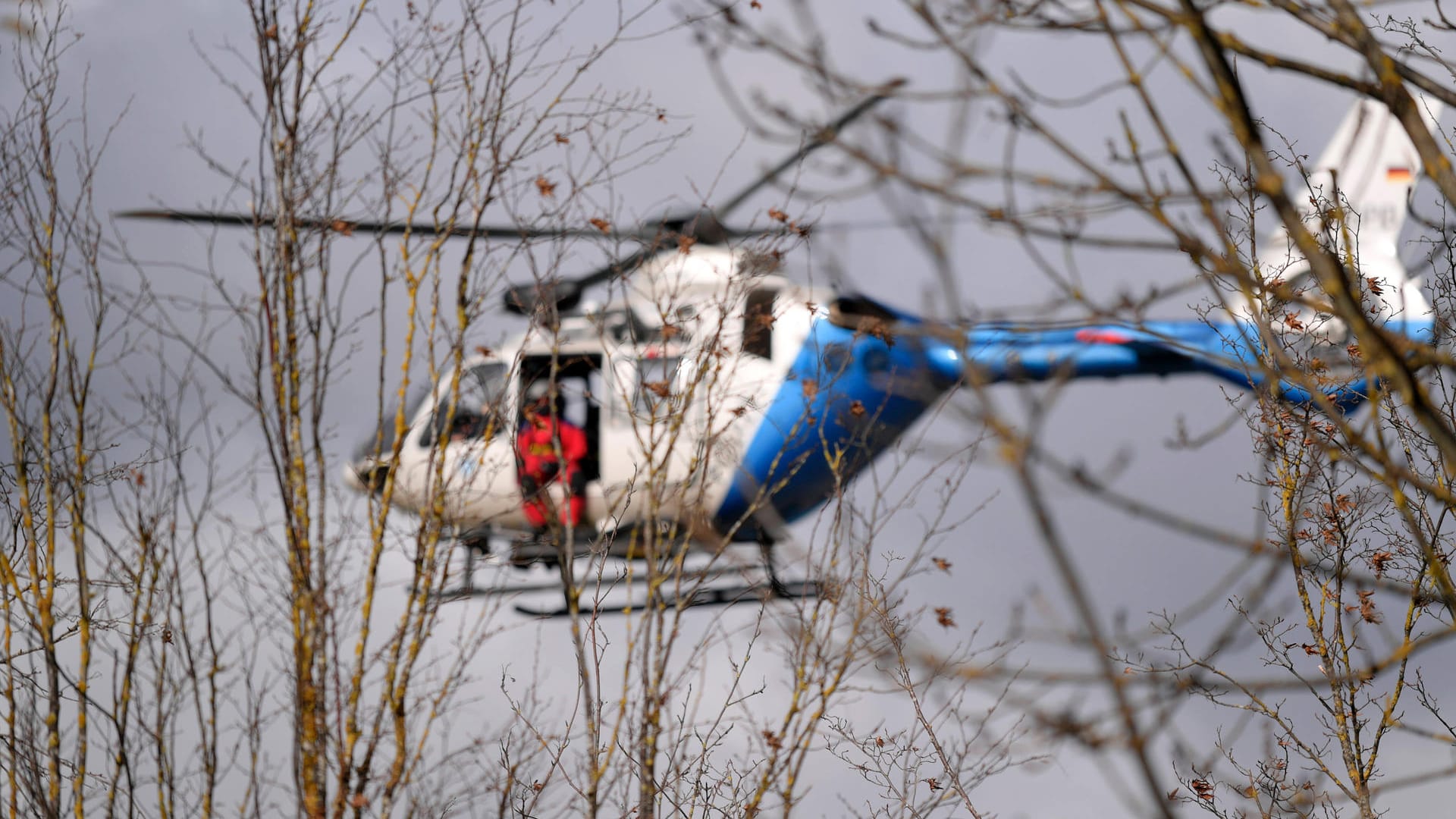Ein Polizeihubschrauber ist durch Bäume zu sehen (Symbolbild): Einer der beiden Männer konnte bisher nicht gefunden werden.
