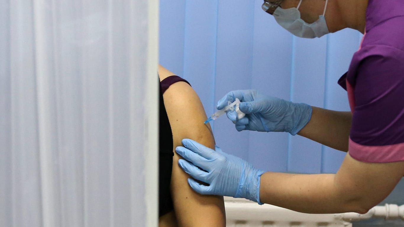 Eine Frau spritzt einer Person in den Arm (Symbolbild): In Wolfsburg werden Helfer für das Impfzentrum gesucht.