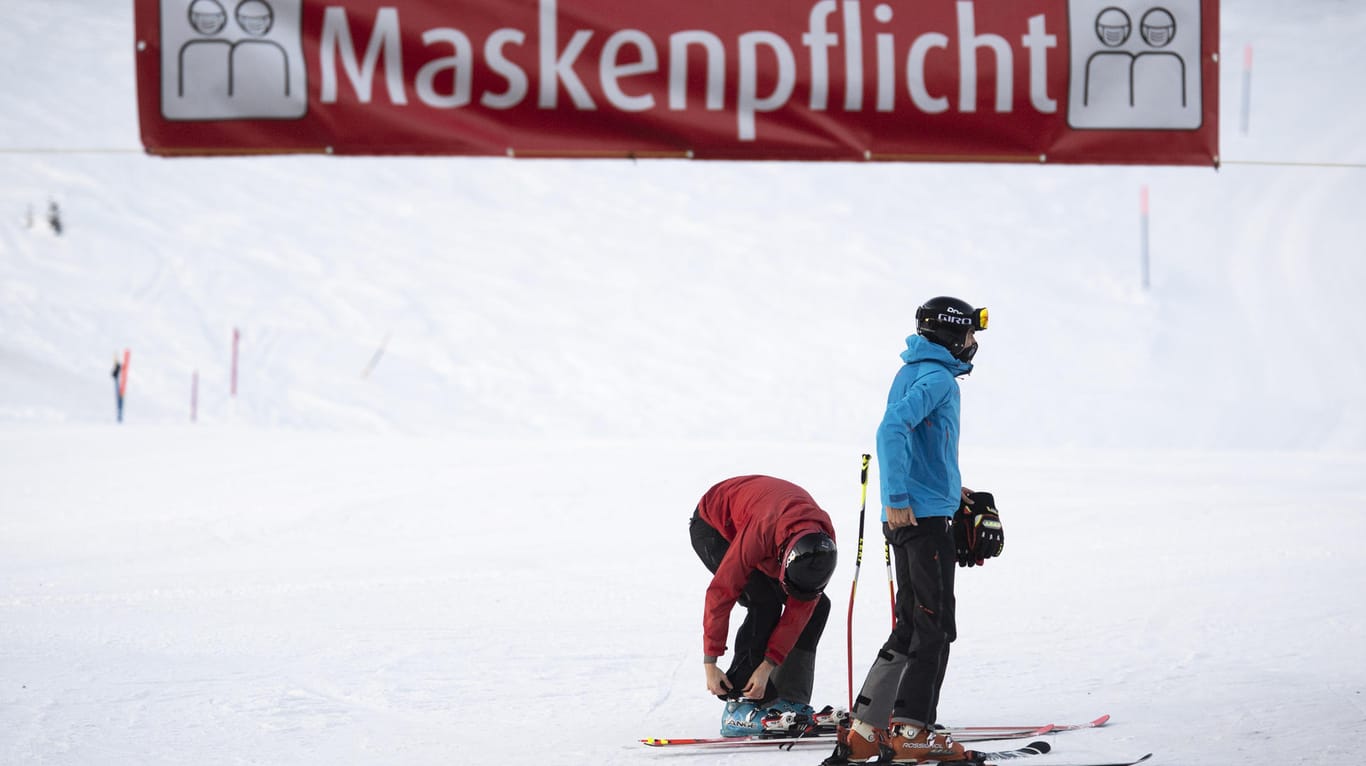 Skifahrer unter einem Maskenpflicht-Banner im Schweizer Skigebiet Flumserberg: Auch dort endet der Sportbetrieb am Dienstag.