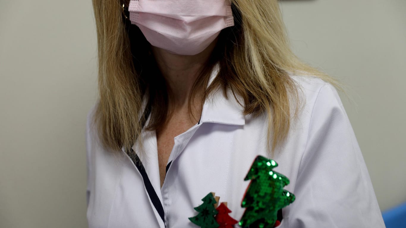 Frau mit Arztkittel, Mund-Nasen-Schutz und weihnachtlichen Ansteckern (Symbolbild): In Essen hat die Polizei eine Weihnachtsfeier in einer Arztpraxis aufgelöst.