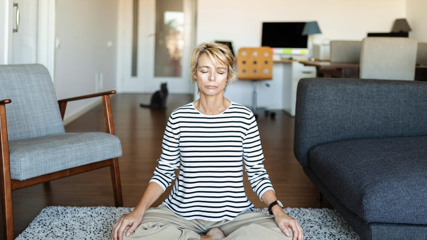 Eine Frau sitzt mit geschlossenen Augen im Schneidersitz: Meditation, Yoga und progressive Muskelentspannung können helfen, wieder die innere Ruhe zu finden.