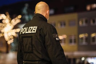 Polizist mit Maske kontrolliert die Ausgangssperre im bayerischen Schweinfurt: In Amberg muss ein Pärchen 1.000 zahlen, weil sie nachts Zigaretten kaufen wollten.