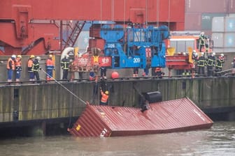 Ein Container schwimmt am Eurogate hinter dem Containerschiff "Delphis Gdansk" im Wasser und wird mit Hilfe eines Krans gesichert: Er war beim Verladen ins Hafenbecken gerutscht.