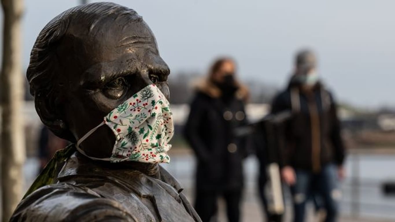 Ein Mund-Nasen-Schutz an einer Statue am Dortmunder Phoenix-See.