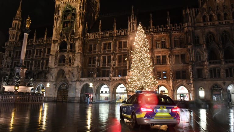 Ein Polizeiauto fährt vor dem Christbaum an Heiligabend über den Münchner Marienplatz: Die Polizei verzeichnete laut Mitteilung nur wenige Verstöße gegen die Ausgangsbeschränkungen, die auch an Weihnachten gelten.