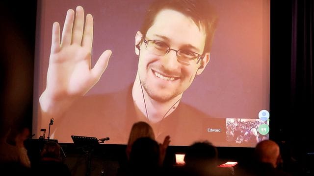 Der NSA-Enthüller Edward Snowden winkt während einer Videoschalte dem Publikum zu.