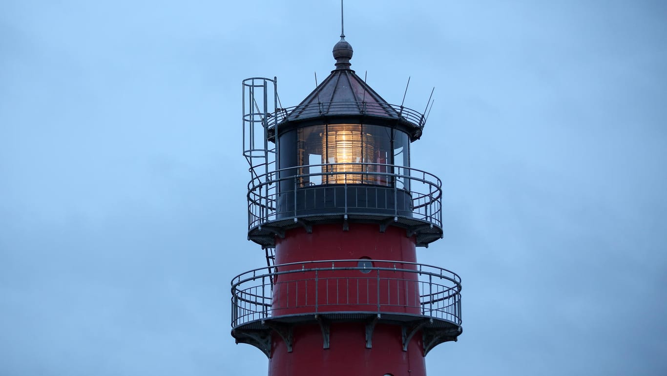 Schleswig-Holstein: Der Leuchtturm von Büsum ist am Morgen bei stürmischem Wetter vor Regenwolken zu sehen.