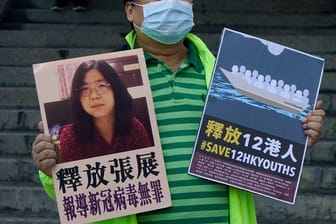 Ein pro-demokratischer Aktivist zeigt zwei Plakate vor dem Verbindungsbüro der chinesischen Zentralregierung.