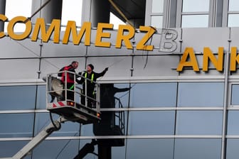 Arbeiter demontieren den Schriftzug einer Commerzbank-Filiale: Die Bank baut drastisch um.