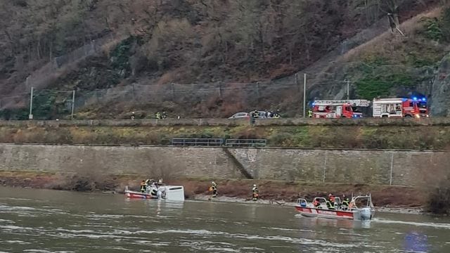 Einsatzkräfte von Feuerwehr und Wasserschutzpolizei kümmern sich um das im Rhein treibende Wohnmobil.