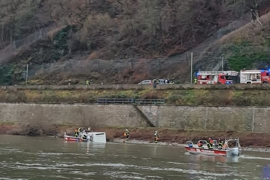 Einsatzkräfte von Feuerwehr und Wasserschutzpolizei kümmern sich um das im Rhein treibende Wohnmobil.